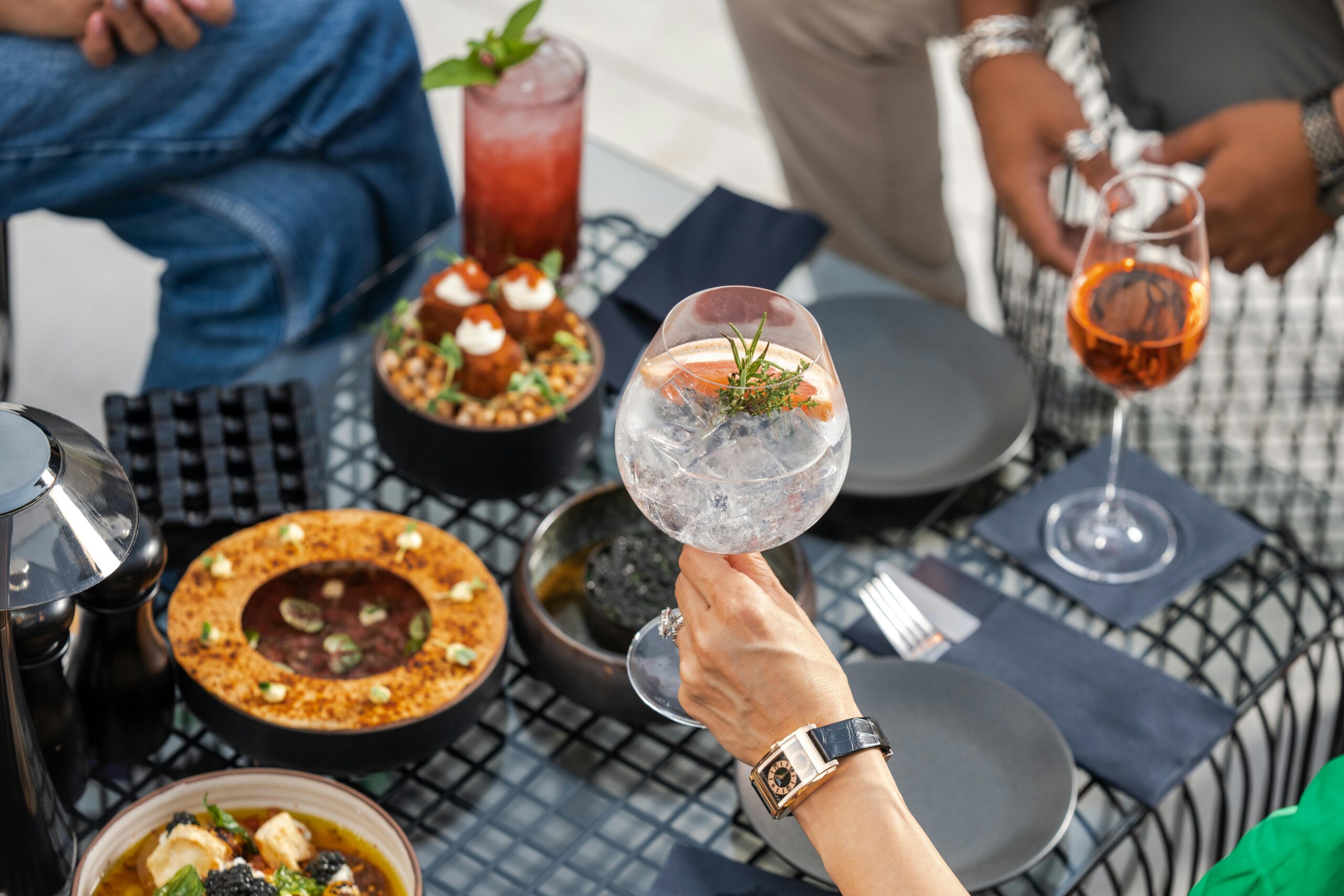 A sophisticated dining setup on a Dubai terrace featuring gourmet dishes and elegant cocktails.
